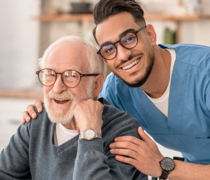 nurse and elderly man smiling and looking at the camera